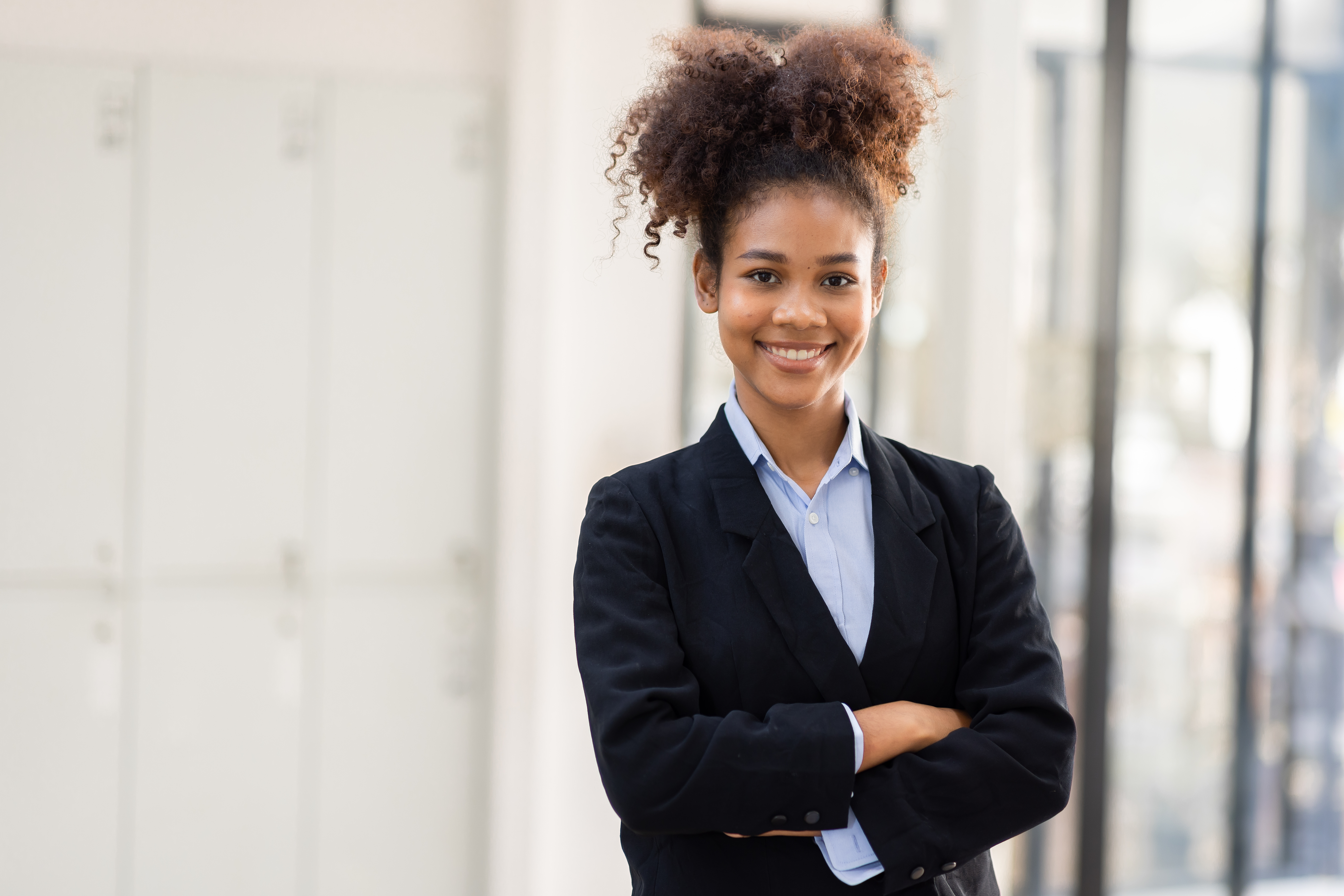 A young business professional standing confidently in an office setting.