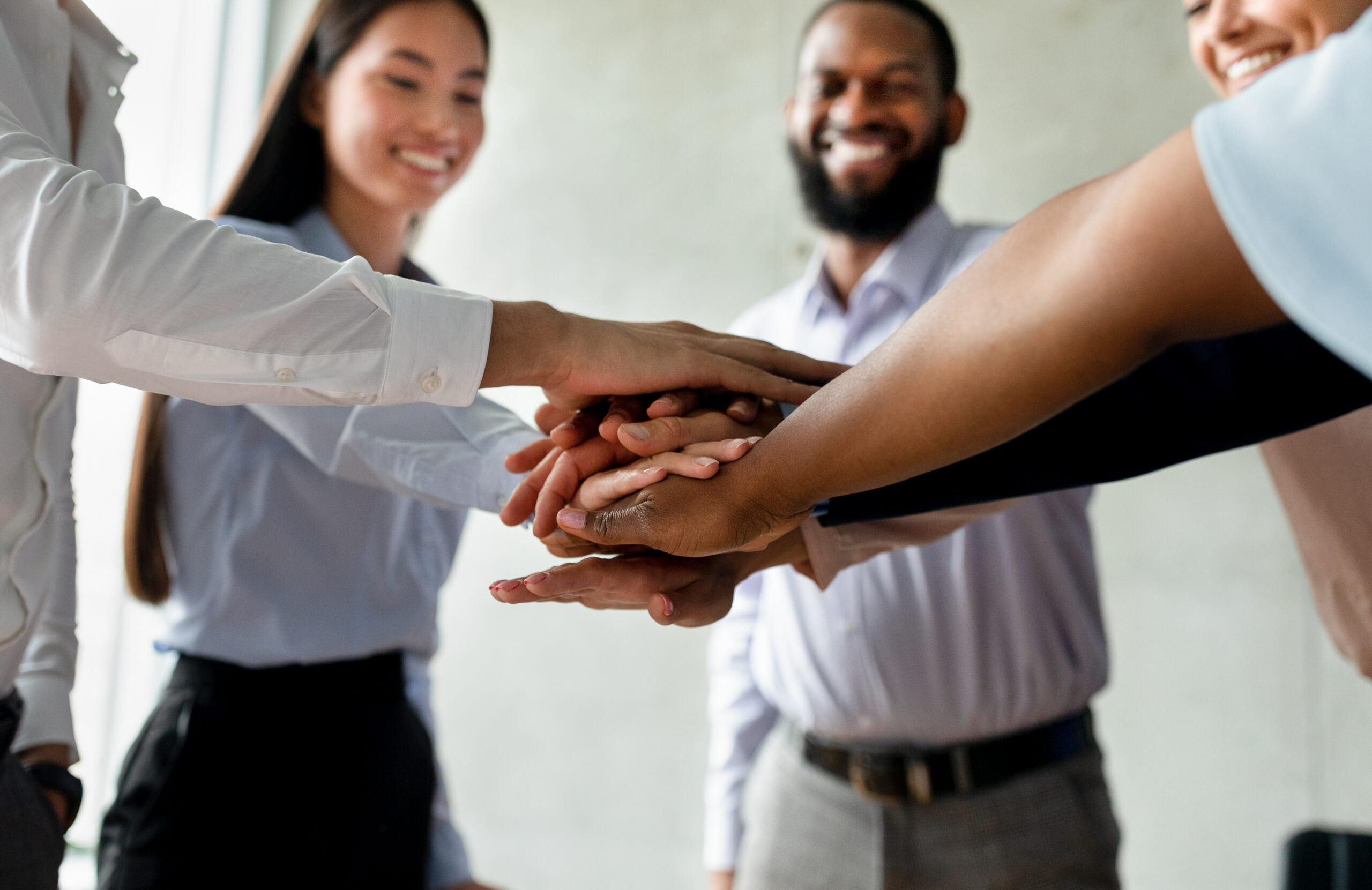 A multi-racial team of business professionals stacking their hands.